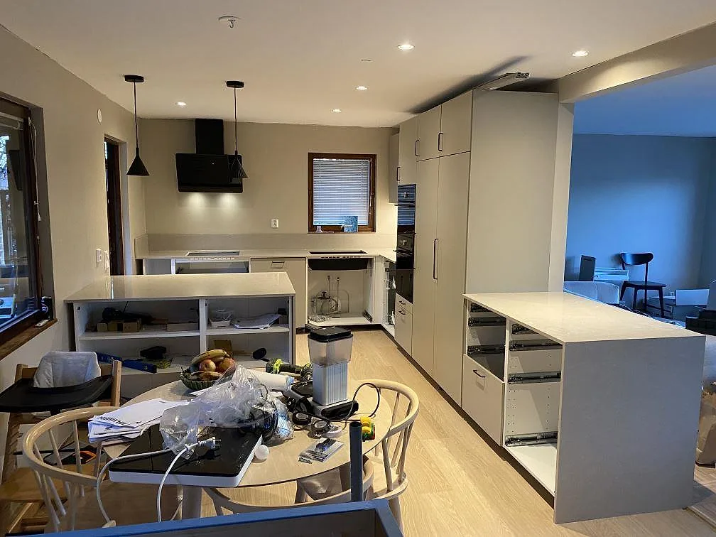 Översikt av kök i Jönköping med polerad köksbänkskiva i Technistone Noble Ivory White, öppna stommar och ljusa arbetsytor under montering.