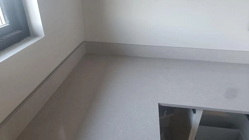 Hörnvy av polerad Technistone Noble Ivory White bänkskiva med stänkkant och ljus ådring i Kalmar.