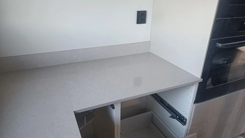 Köksbänk i polerad Technistone Noble Ivory White vid ugn och öppna köksstommar under montering i Kalmar.