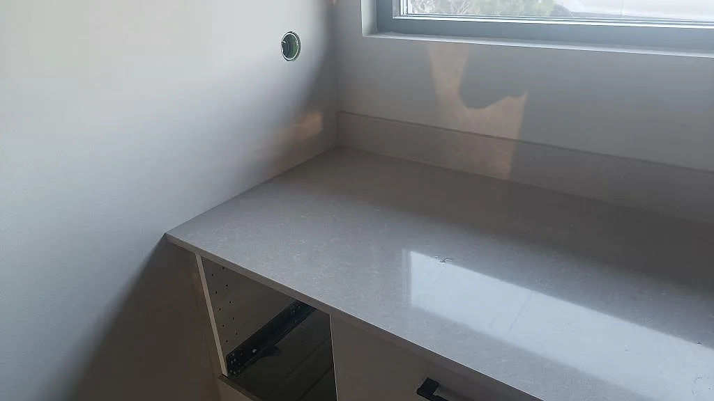Ljus köksbänkskiva i Technistone Noble Ivory White, polerad kvartskomposit, med uppvikt stänkkant vid fönster i Kalmar.
