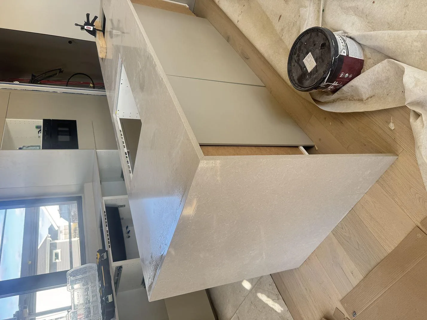 Sidovy av köksön i Technistone Noble Ivory White, polerad kvartskomposit med ljus stenklädd gavel under montering i Kalmar.