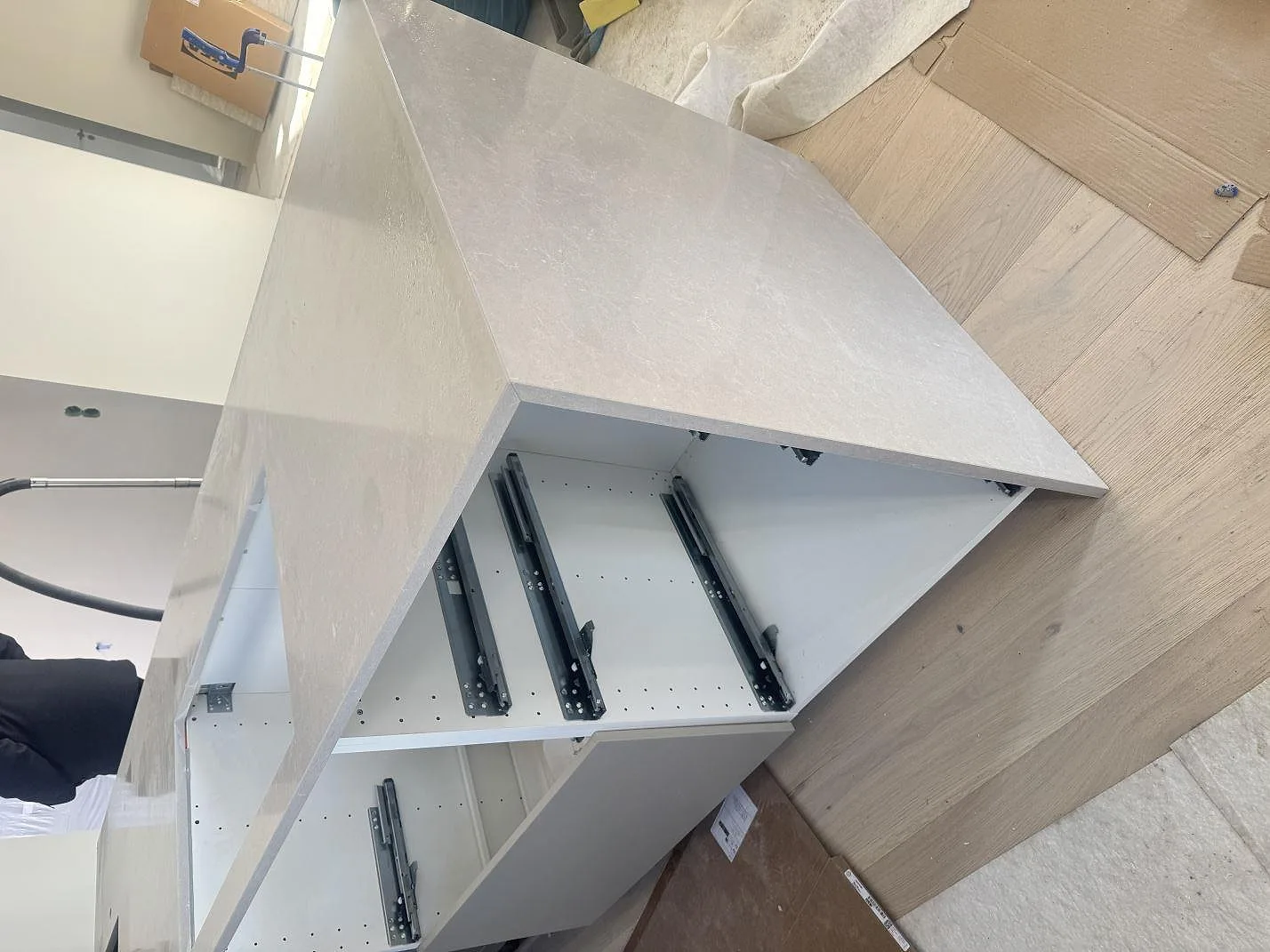 Detalj av stenklädd köksö i polerad Technistone Noble Ivory White med ljus gavel och öppna lådstommar i Kalmar.