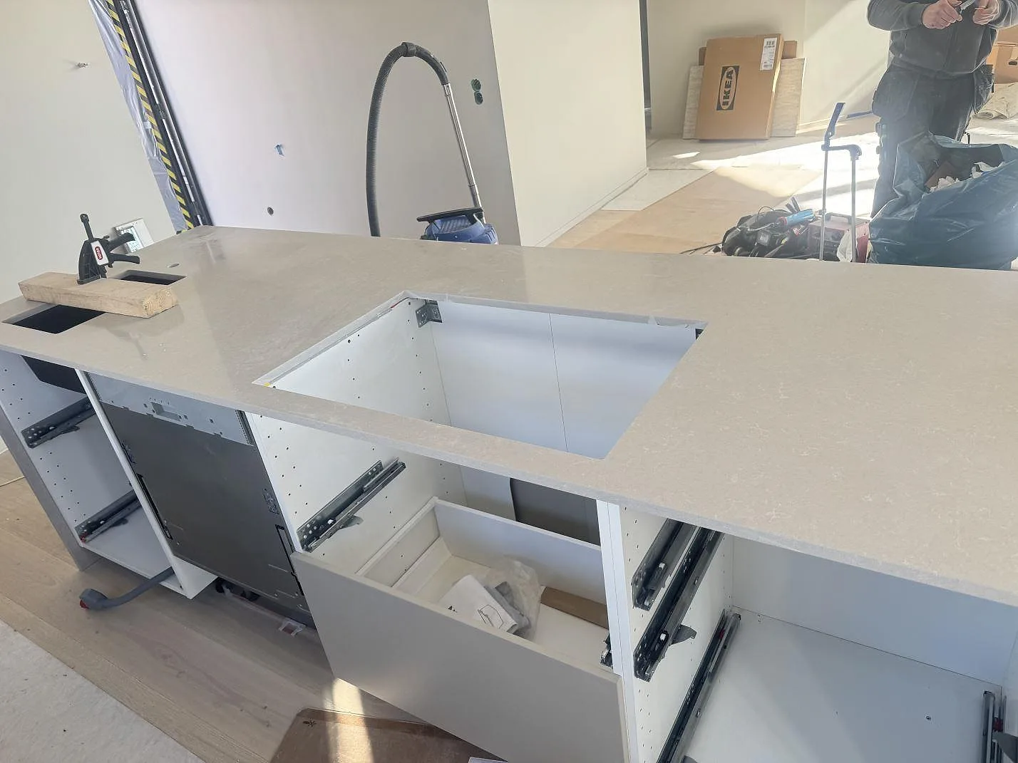 Närbild av installerad köksbänkskiva i Technistone Noble Ivory White med stor rektangulär öppning och öppna stommar under montering i Kalmar.