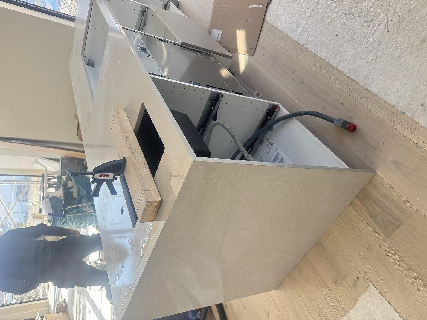 Installerad köksö i Technistone Noble Ivory White, polerad ljus kvartskomposit, med öppna köksstommar under montering i Kalmar.