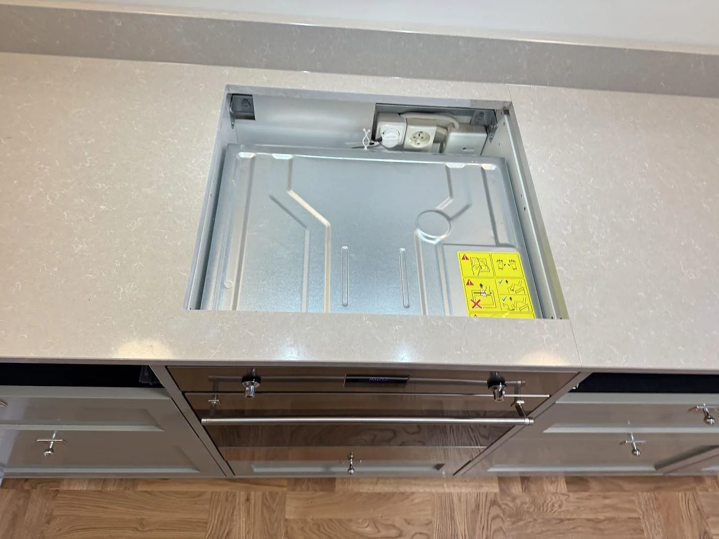 Urtag för spishäll i en polerad köksbänkskiva i Technistone Noble Ivory White i ett kök i Kalmar, sett uppifrån under montering.