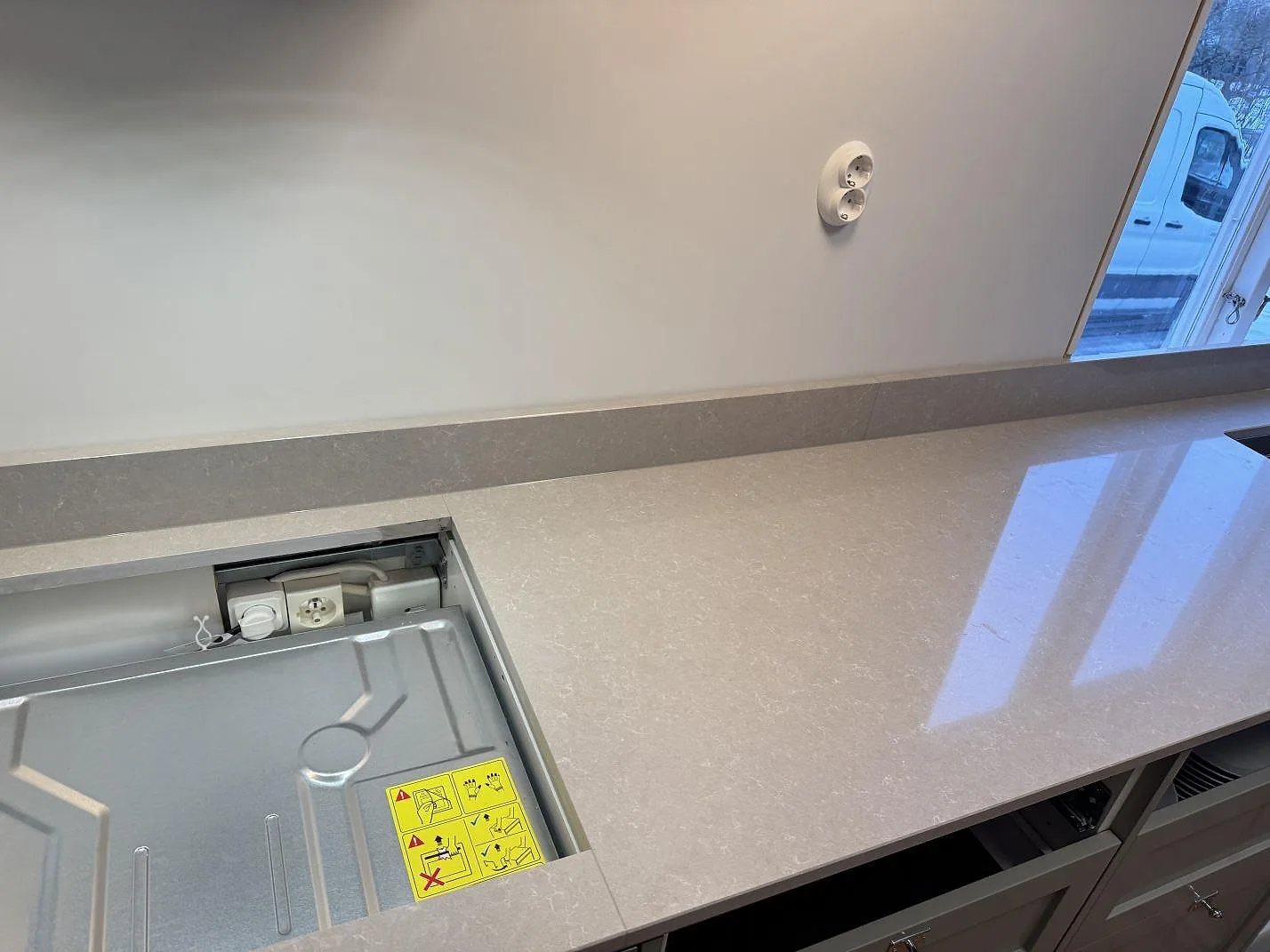 Köksbänkskiva i Technistone Noble Ivory White i Kalmar med urtag för häll i bänken och vinterfönster med utsikt mot gården.