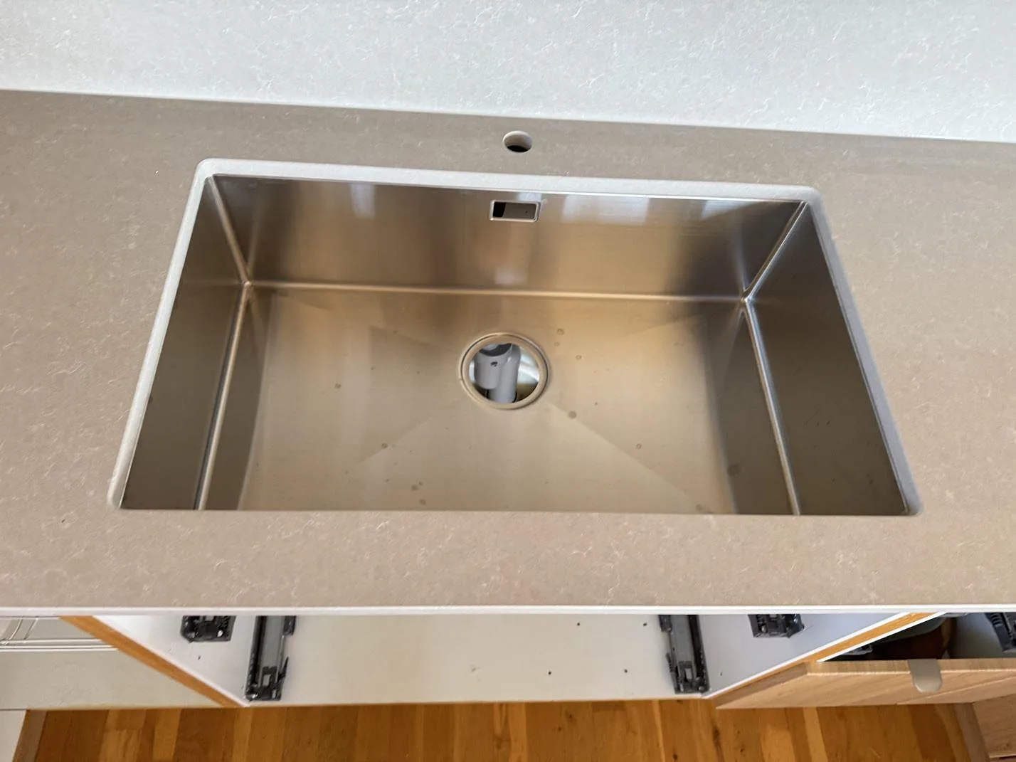 Närbild på underlimmad rostfri diskho i en polerad Technistone Noble Ivory White-kompositskiva i kök i Karlshamn.