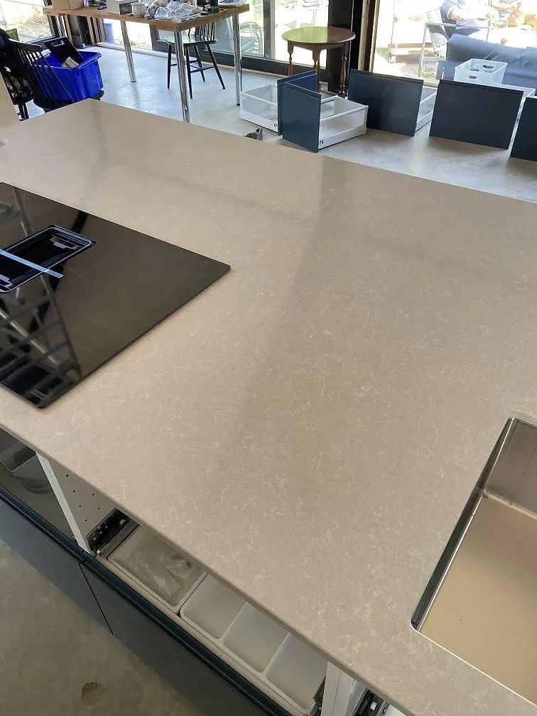 Köksö i Technistone Noble Ivory White med underlimmad rostfri diskho och borrat blandarehål i ett kök i Kivik.