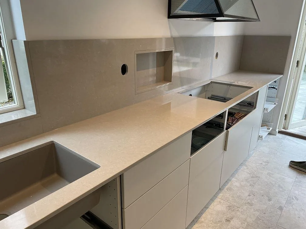 Köksbänkskiva i Technistone Noble Ivory White, polerad komposit, med stor köksö och väggbänk i ett kök i Klagshamn.