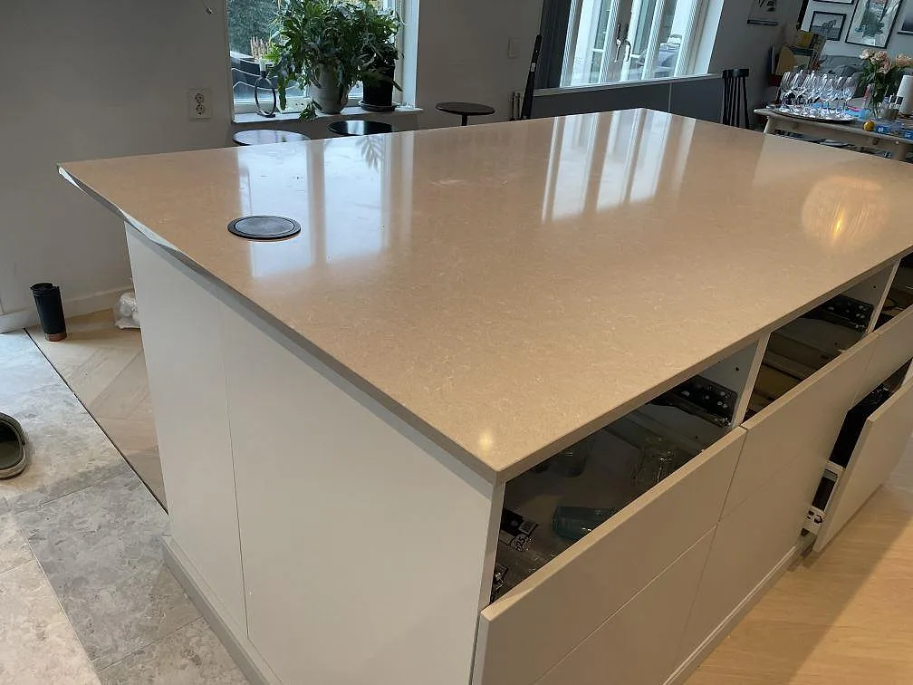 Närbild på köksö i Technistone Noble Ivory White, polerad 20 mm komposit, i ett ljust kök i Klagshamn.