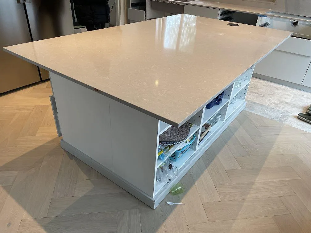 Stor köksö i polerad Technistone Noble Ivory White komposit på vit köksinredning i Klagshamn.