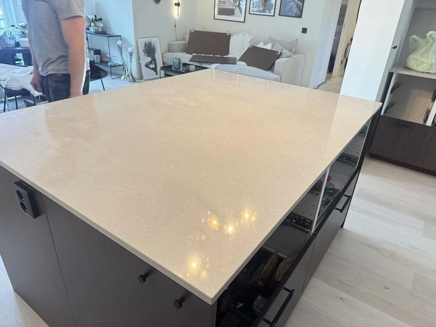 Polerad köksö i Technistone Noble Ivory White med ljus ådring och mörka stommar i ett öppet kök i Kungsbacka.