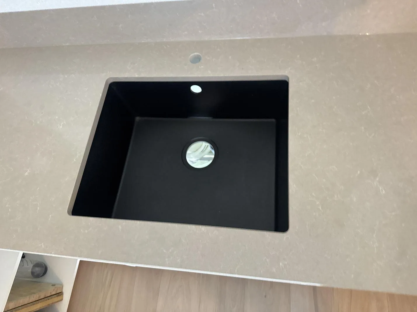Närbild på svart diskho och blandarhål i polerad Technistone Noble Ivory White, kompositbänkskiva i Kungsbacka.