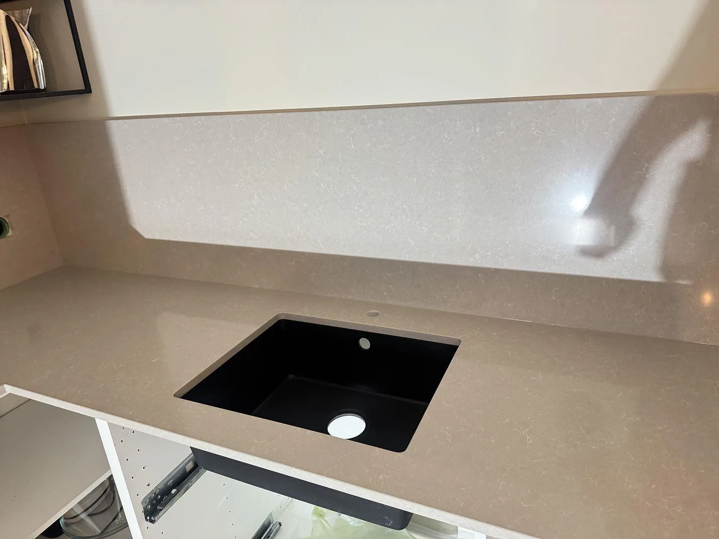 Väggbänk i polerad Technistone Noble Ivory White med svart diskho och matchande stänkskydd i köket i Kungsbacka.