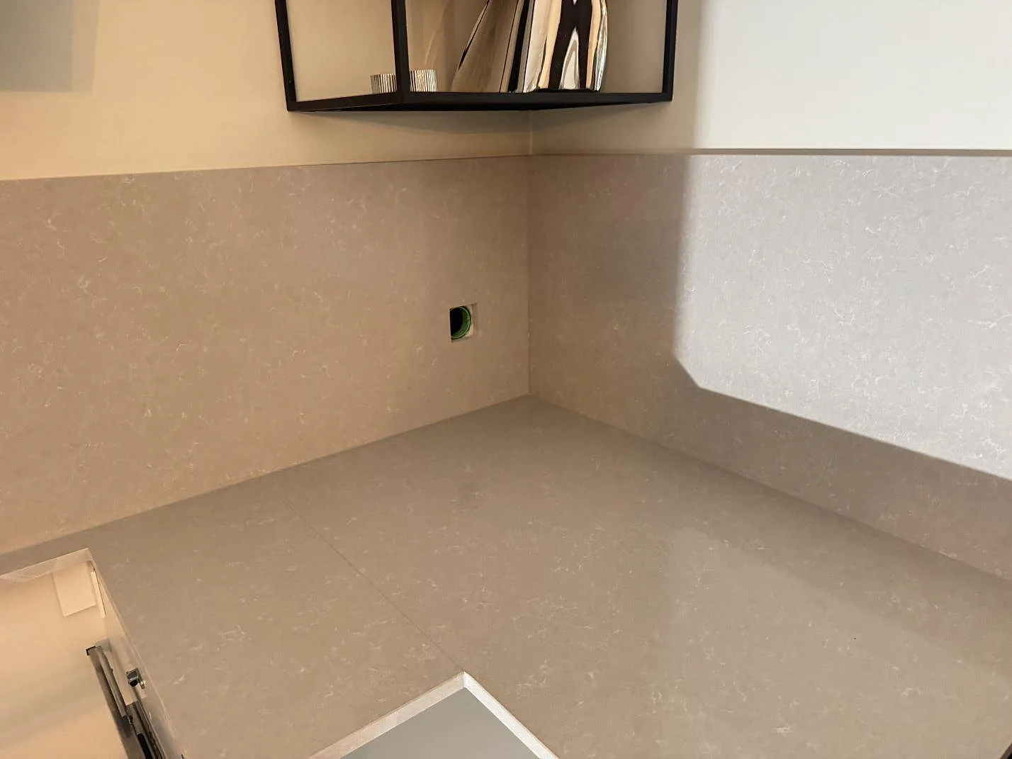 Hörnsektion med polerad Technistone Noble Ivory White som bänkskiva och stänkskydd under öppen hylla i Kungsbacka.