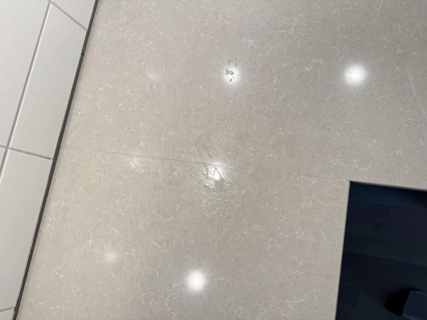 Närbild av skarv och ådring i polerad Technistone Noble Ivory White kvartskomposit på en köksbänk i Landskrona.