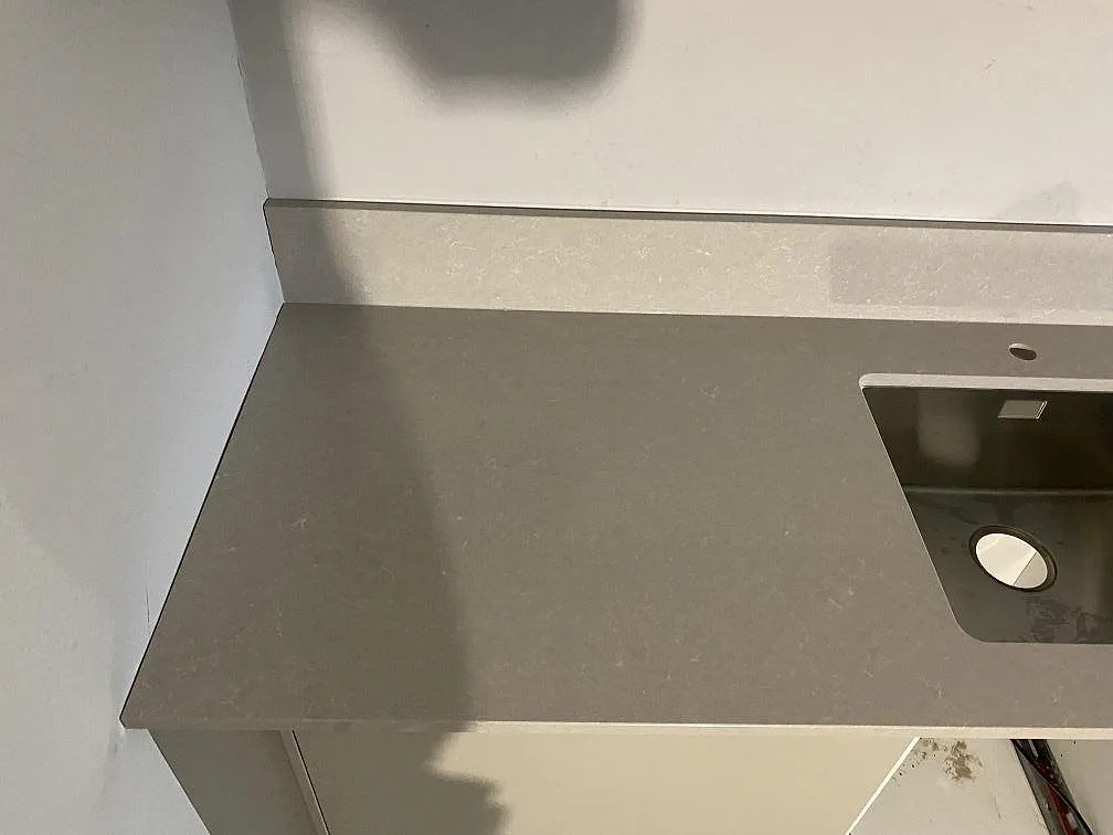 Detalj av polerad Technistone Noble Ivory White bänkskiva med rostfri diskho och svag ådring i köket i Limhamn.