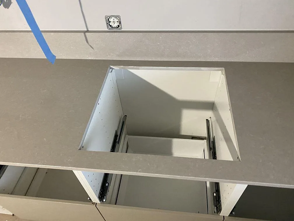 Hällöppning i köksbänkskiva av polerad Technistone Noble Ivory White med öppna köksstommar i Limhamn.