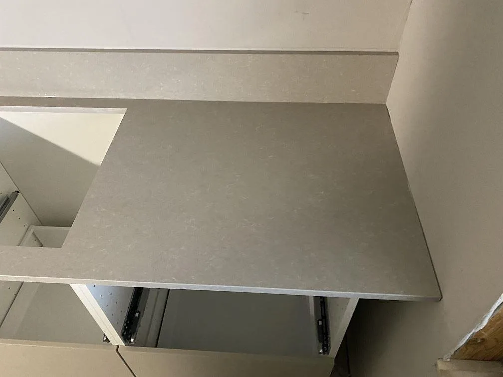 Höger del av polerad Technistone Noble Ivory White köksbänkskiva med rak avslutning och låg stänkkant i Limhamn.