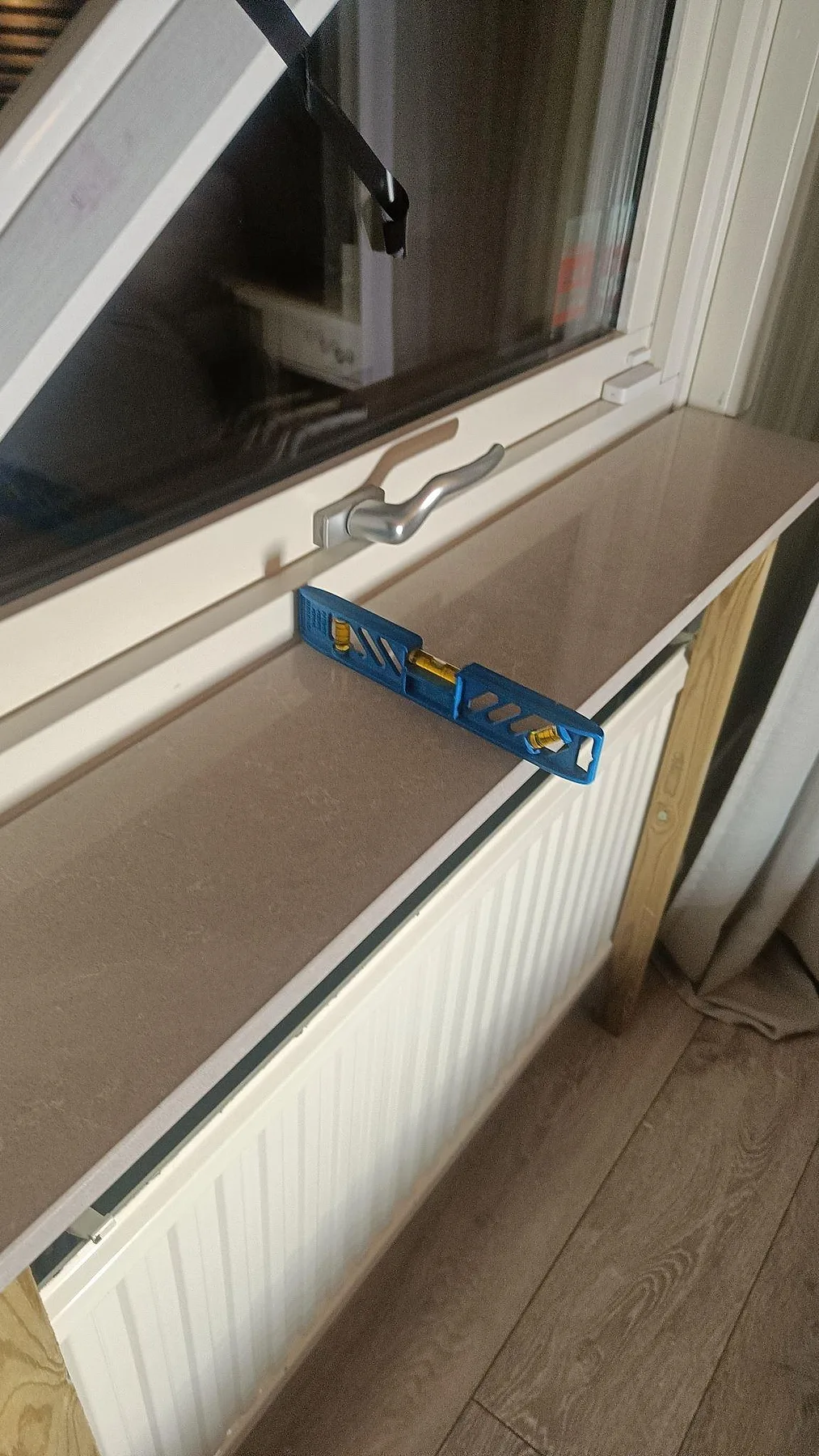 Närbild av monterad fönsterbänk i Technistone Noble Ivory White med vattenpass på polerad ljus komposit i Löddeköpinge.
