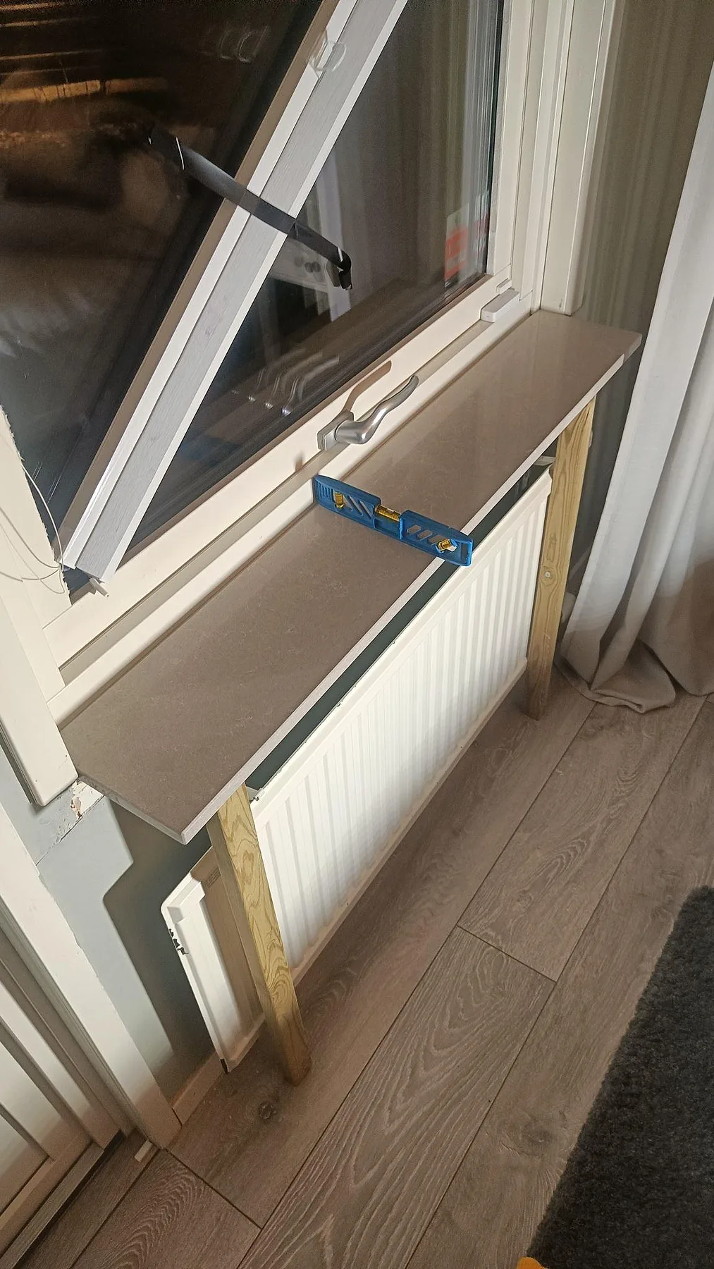 Fönsterbänk i 20 mm Technistone Noble Ivory White under montering, med vattenpass på den polerade kompositytan i Löddeköpinge.
