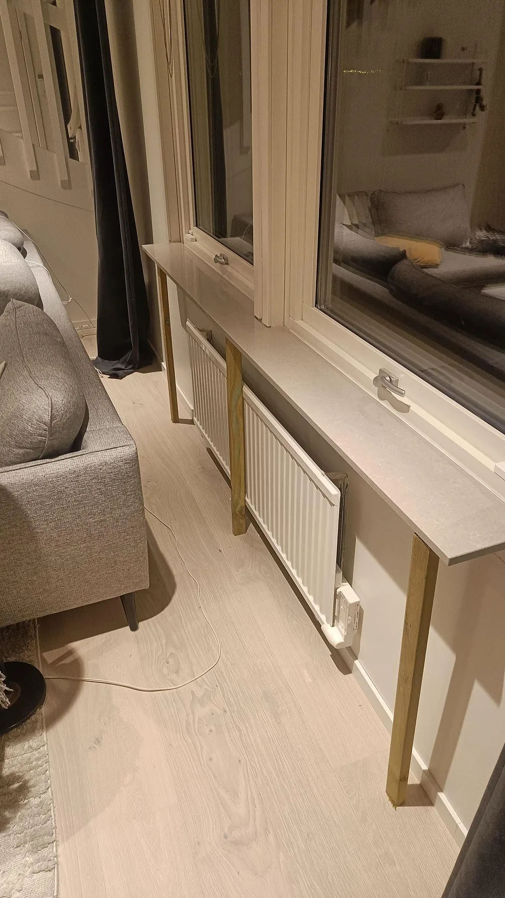 Polerade fönsterbänkar i Technistone Noble Ivory White, ljus kompositsten, monterade ovanför radiatorer i ett vardagsrum i Löddeköpinge.