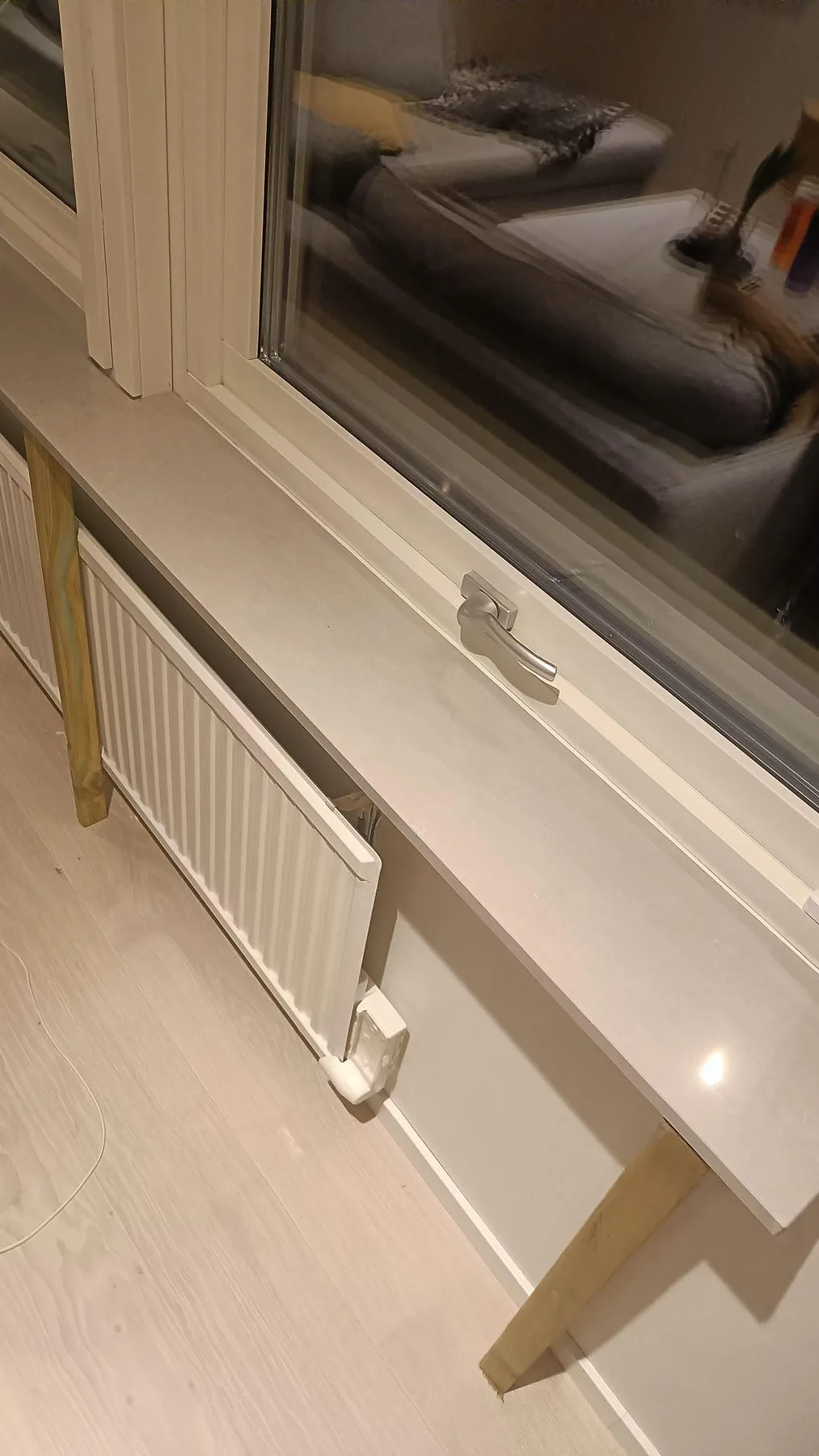 Detalj av polerad fönsterbänk i Technistone Noble Ivory White med ljus komposityta och radiator under i Löddeköpinge.