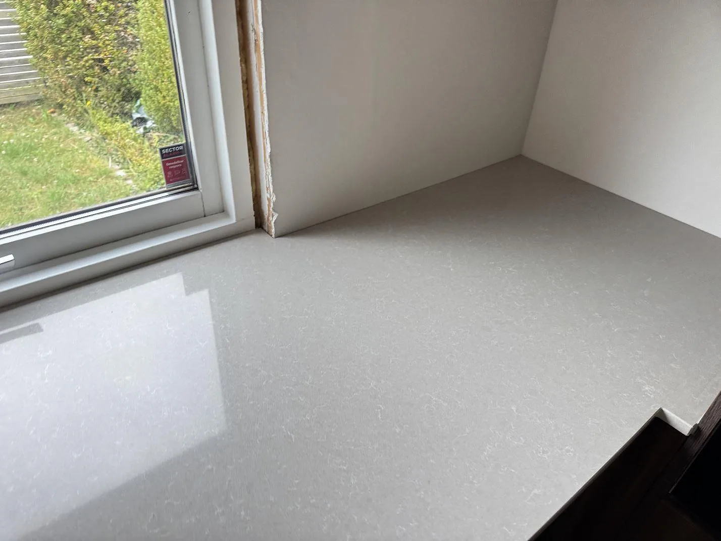 Fönstersida med installerad köksbänkskiva i polerad Technistone Noble Ivory White komposit i Löddeköpinge.