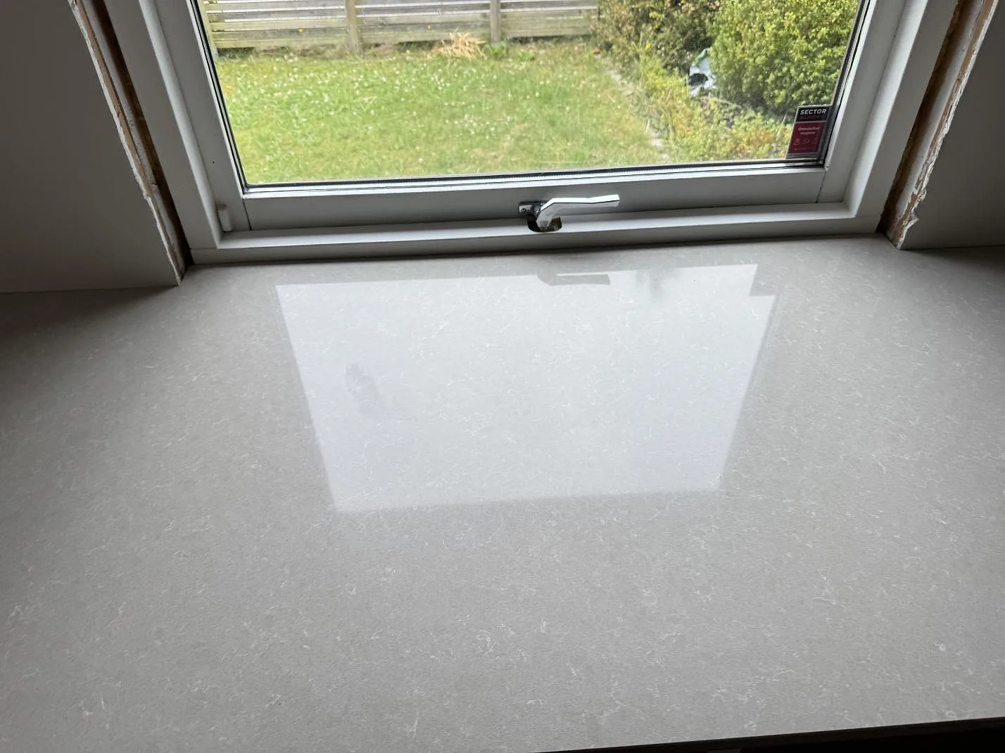 Topvy över polerad Technistone Noble Ivory White komposit under fönster, med ljus ådring i Löddeköpinge.