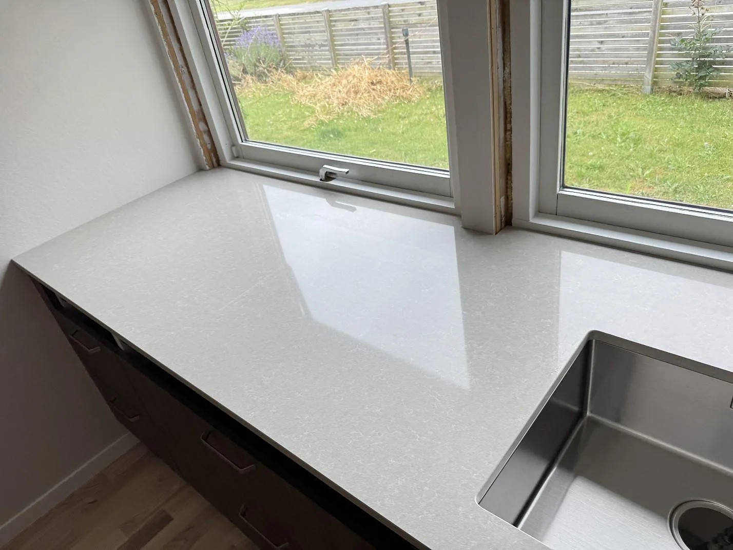 Polerad Technistone Noble Ivory White bänkskiva med diskho, fönsternisch och speglingar i köket i Löddeköpinge.