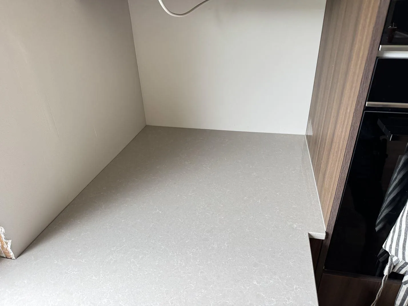 Hörnvy av polerad Technistone Noble Ivory White bänkskiva mot sidovägg och högskåp i köket i Löddeköpinge.