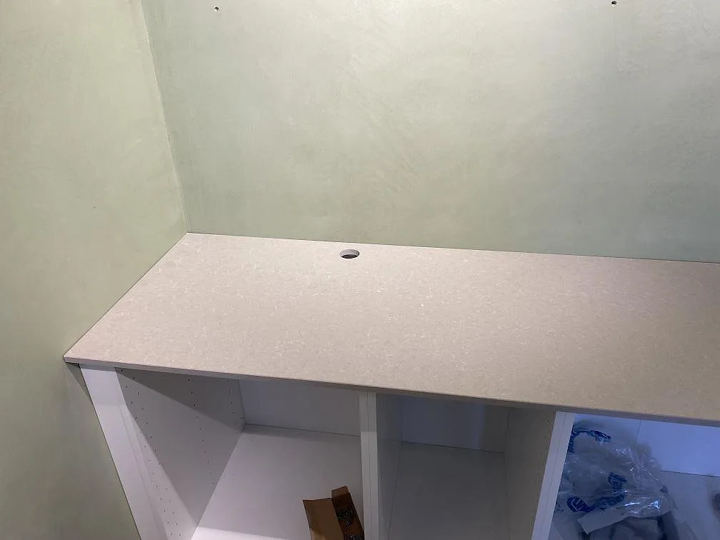 Lång bänksträcka i polerad Technistone Noble Ivory White med synligt blandarhål på vita köksstommar i Lomma.