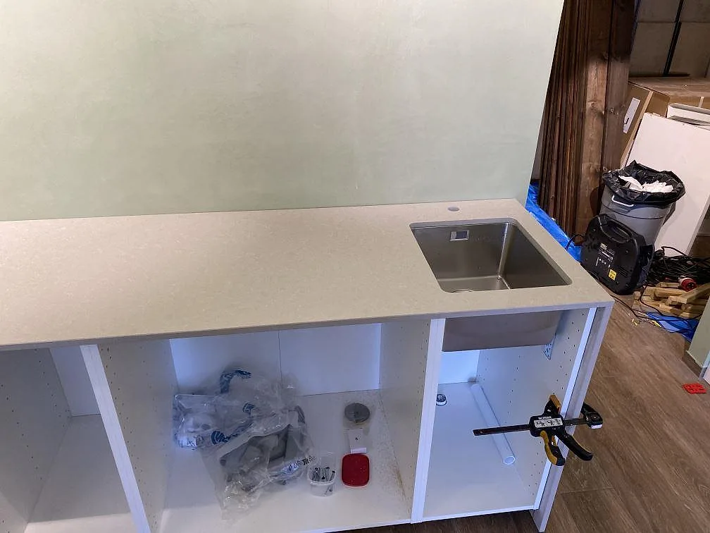 Närbild på polerad Technistone Noble Ivory White med underlimmad rostfri diskho och blandarhål i köket i Lomma.