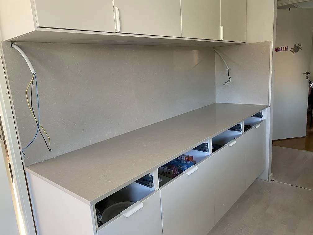 Rak köksbänkskiva i polerad Technistone Noble Ivory White, komposit, med hög väggbeklädnad under överskåp i Lomma.