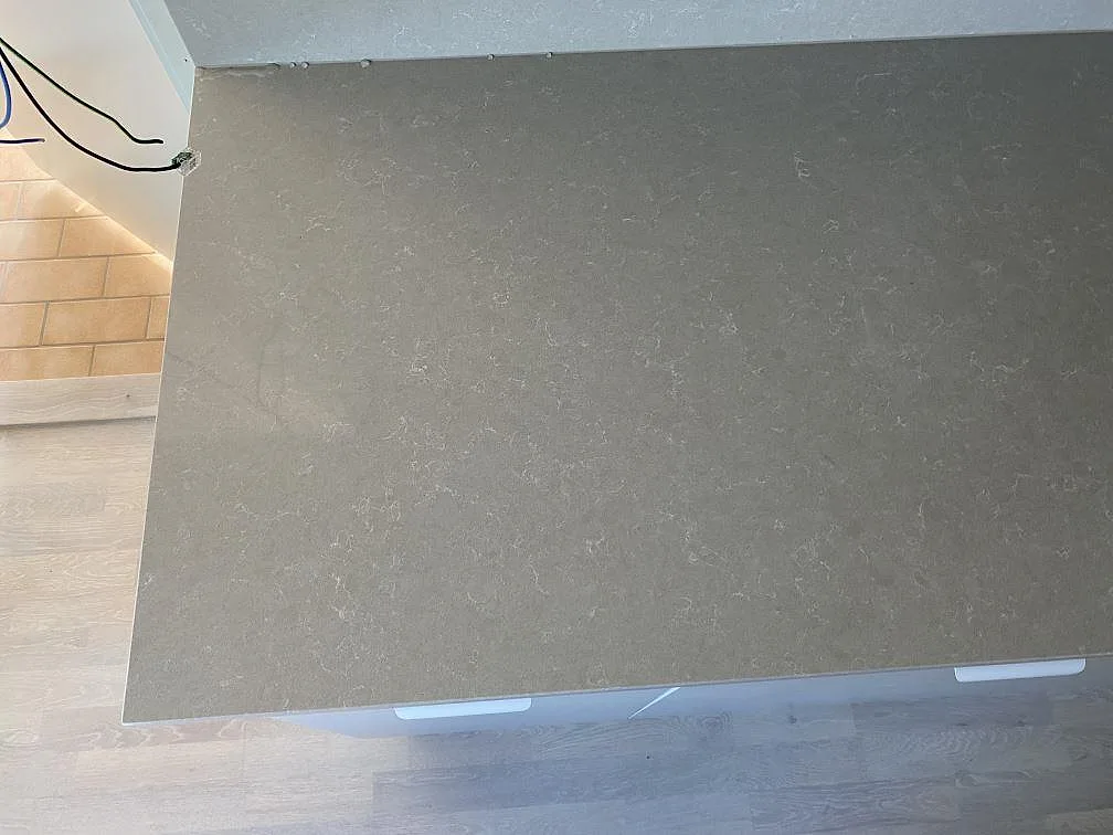 Ovanifrån syns den polerade ytan i Technistone Noble Ivory White, komposit, på en monterad köksbänkskiva i Lomma.