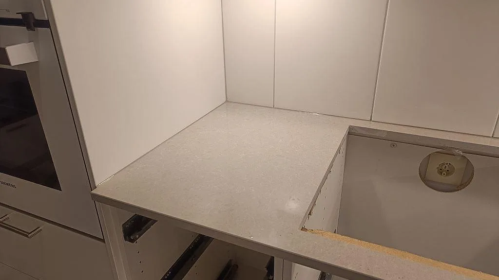 Polerad Technistone Noble Ivory White bänkskiva med hälluttag och ljus komposityta mot vitt kakel i ett kök i Lund.