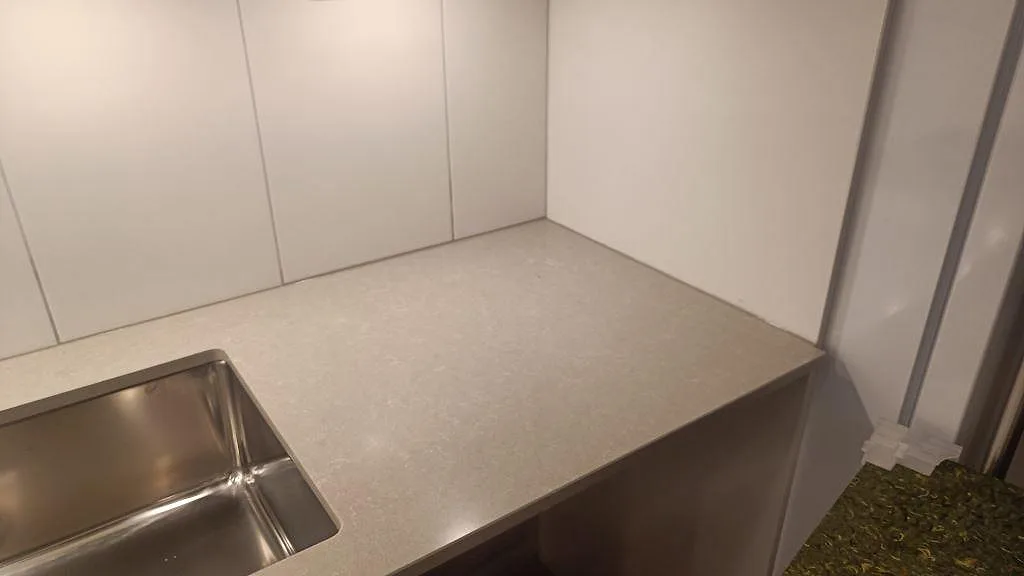 Diskbänkssida med rostfri underlimmad ho och polerad Technistone Noble Ivory White arbetsyta i Lund.