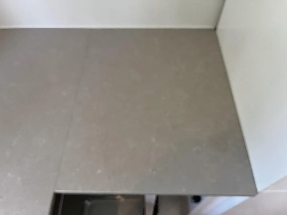 Närbild på köksbänkskiva i Technistone Noble Ivory White med infälld svart induktionshäll och vit ådring, polerad kvartskomposit i ett kök i Malmö.