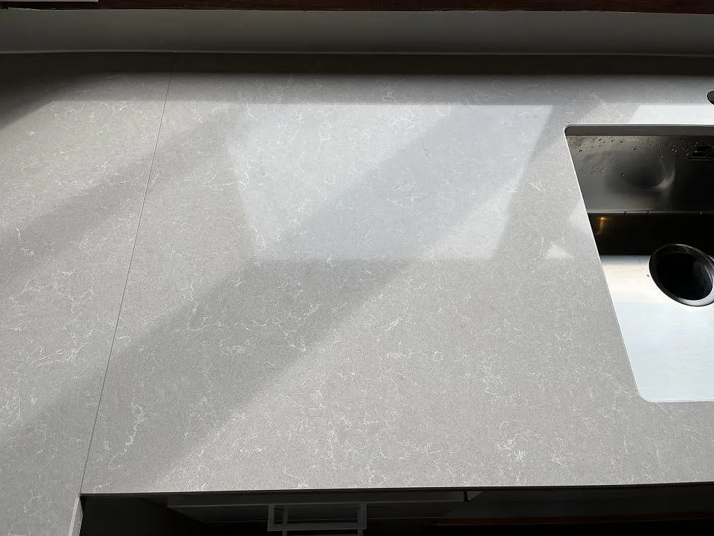 Installerad köksbänkskiva i Technistone Noble Ivory White ovanifrån, ljus gråvit kvartskomposit med vit ådring, i ett kök i Malmö.