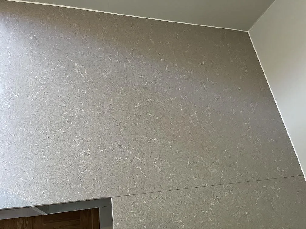 Köksbänkskiva i Technistone Noble Ivory White med underlimmad rostfri diskho och mjuk vit ådring, ljus kvartskomposit i ett kök i Malmö.