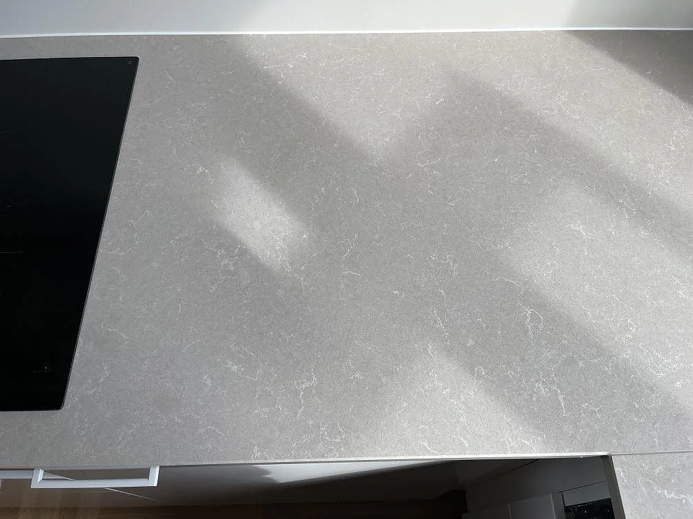 Köksbänkskiva i Technistone Noble Ivory White med infälld induktionshäll, ljus kvartskomposit i ett kök i Malmö, fotograferat under montering.