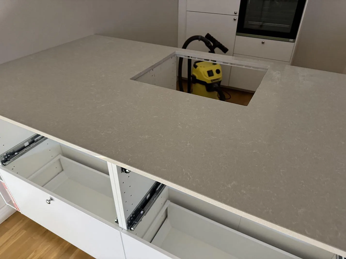 Installerad köksbänkskiva i polerad Technistone Noble Ivory White med rektangulärt urtag och öppna vita stommar under montering i Malmö.