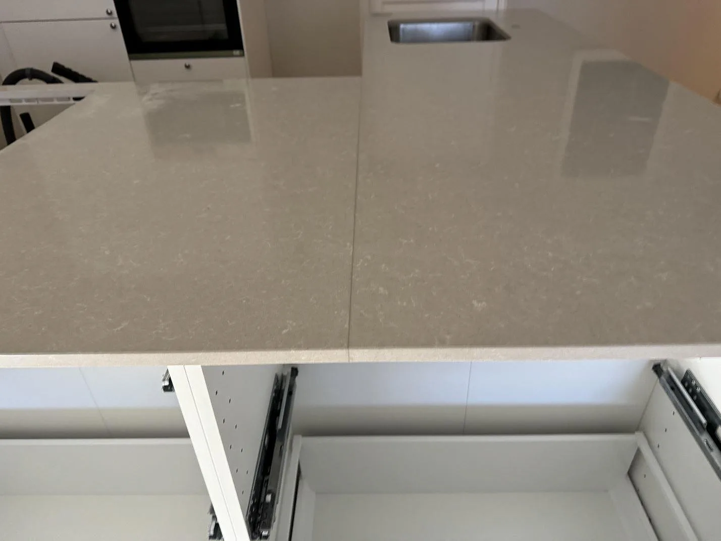 Blankpolerad yta i Technistone Noble Ivory White på köksö med öppen vit inredning och rostfri diskho i bakgrunden i Malmö.