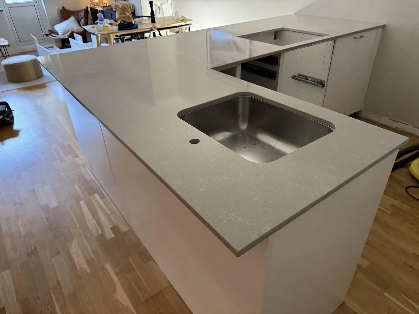 Köksbänkskiva i polerad Technistone Noble Ivory White, varm ljus kvartskomposit, med köksö och underlimmad rostfri diskho i ett kök i Malmö.