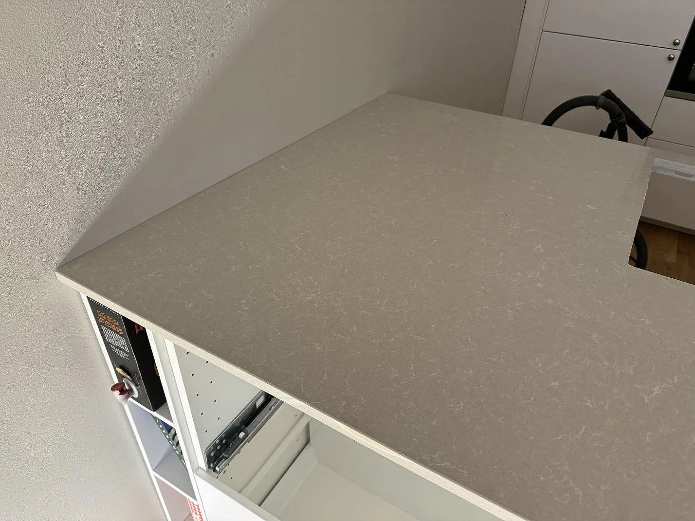 Polerad köksbänkskiva i Technistone Noble Ivory White med varm ljus yta och vita köksstommar under montering i Malmö.