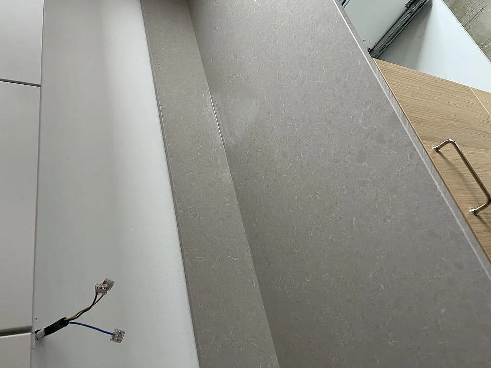 Lång bänkyta i polerad Technistone Noble Ivory White komposit längs vita köksstommar i Malmö.