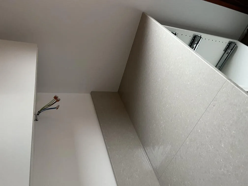 Närbild på den ljusa kompositytan Technistone Noble Ivory White och kantdetalj under köksmontering i Malmö.