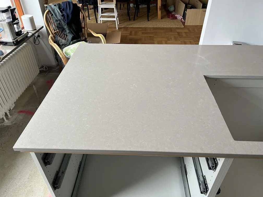 Köksbänkskiva i polerad Technistone Noble Ivory White komposit med diskhoöppning i ett kök under montering i Malmö.