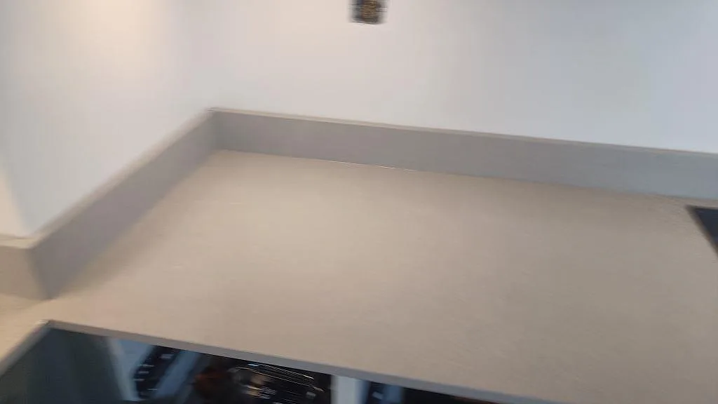 Detalj av polerad Technistone Noble Ivory White med stänkkant och hällkant under montering i Malmö.