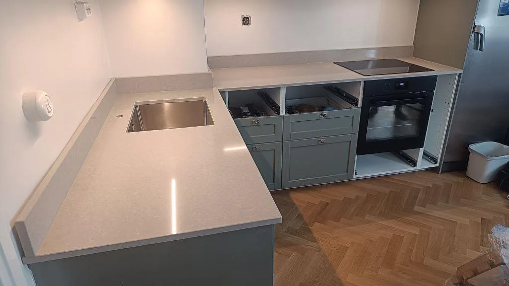 Köksbänkskiva i Technistone Noble Ivory White, polerad kvartskomposit, med underlimmad rostfri diskho och svart häll i Malmö.